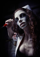 Horror shot: ugly evil crazy nurse (doctor) in bloody uniform killing by syringe. Zombie woman (living dead). Monster from nightmare. Grunge texture effect