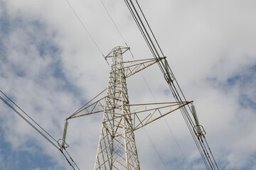 Energy industry, high voltage wires on electrical supports, sky with clouds, no person
