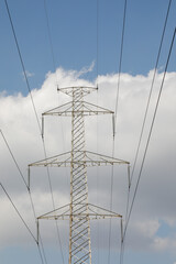 high voltage mast with power lines of blue sky with clouds, vertical format