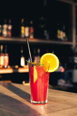 Serving fresh red, purple summer fruit cocktail at bar counter on sunny day. Selected focus, shallow depth of field.