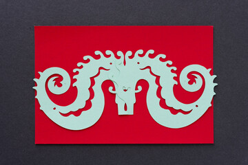 two paper seahorses overlapping on red and dark gray paper