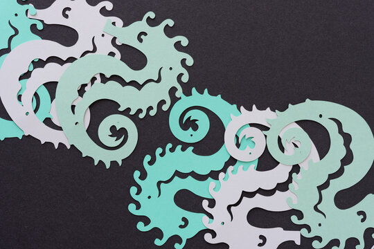 several paper seahorses on dark gray paper