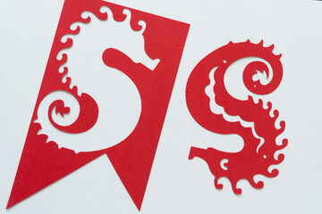 stencil banner with paper seahorse cutout and upside down red paper seahorse on white paper