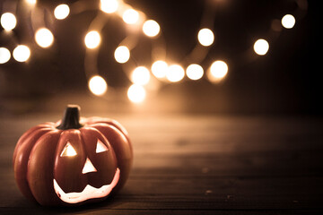 Halloween pumpkin wallpaper with string lights bokeh in the background. Toned vintage colors, copy...