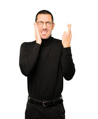 Concerned young man doing a crossed fingers gesture