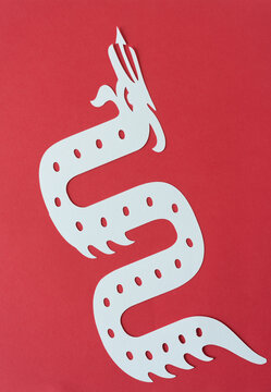 paper silhouette of mythological creature (serpent) on red