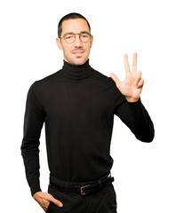 Young man making a number three gesture