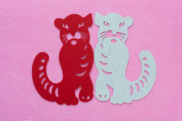 two stylized tiger glyphs isolated on pink felt