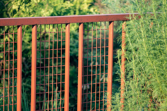 Red metal fence in a private garden. Garden natural background.