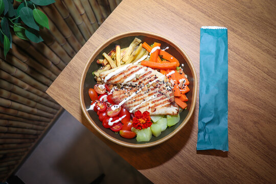 Prato gourmet de frango grelhado com salada em uma mesa de madeira