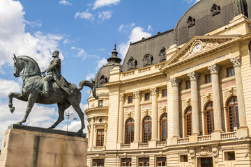 Fototapeta na wymiar Bucharest, Romania June 2022: Statue of King Carol I in Bucharest, Calea Victoriei in front of the National Library building.
