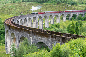 Fototapeta na wymiar Jacobite steam train,entering Glenfinnan Viaduct,set amongst Scottish Highland scenery,Glenfinnan, Inverness-shire, Scotland, UK.