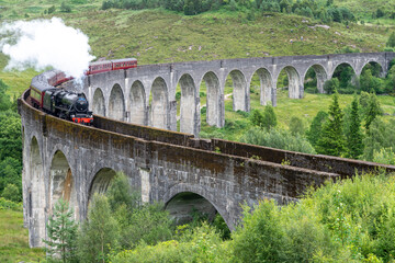Jacobite locomotive train,blowing steam,crossing Glenfinnan Viaduct,amongst Scottish Highland scenery,Glenfinnan,Inverness-shire, Scotland.