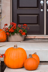 Orange pumpkins on display on steps of front porch of a house