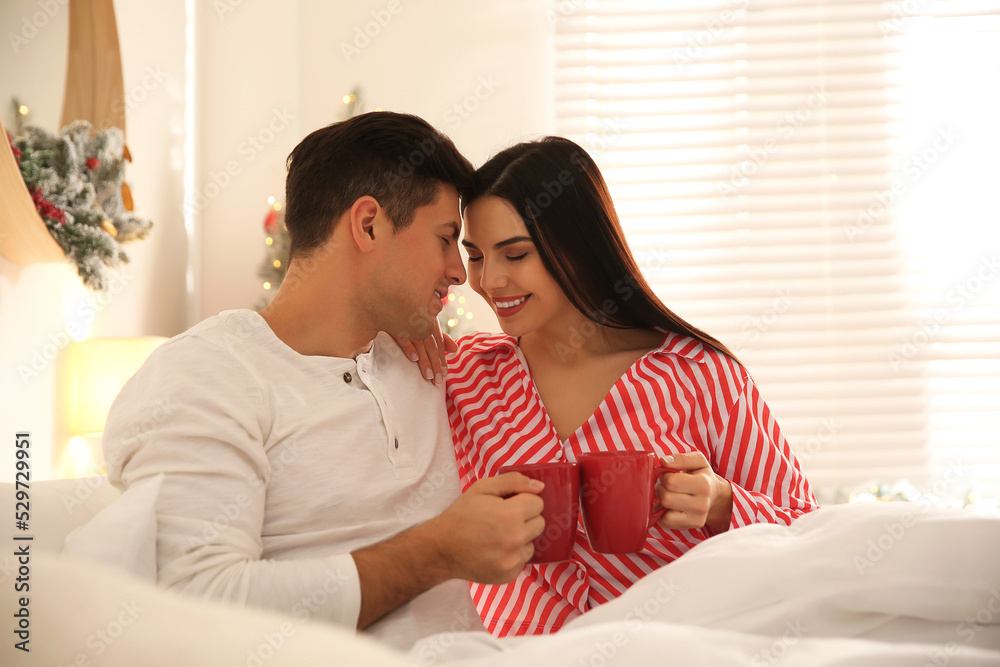 Wall mural happy couple with cups in bed. christmas celebration