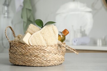 Natural loofah sponges and soap bar in wicker basket on table indoors