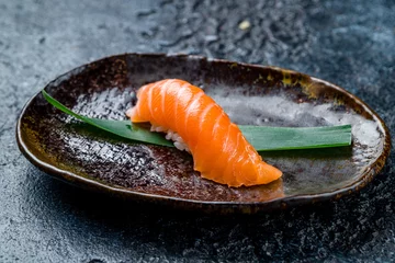 Fototapeten sushi salmon on a plate on dark stone table © bbivirys