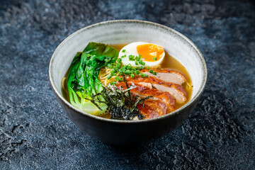 duck soup with egg and greenery on dark stone table