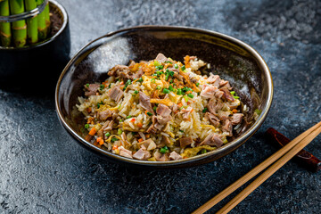 fried rice with duck on dark stone table