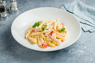 Penne with salmon and creamy sauce on grey table