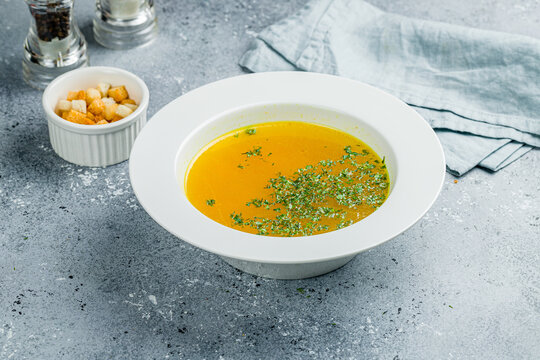 Chicken soup bouillon in a plate on grey table