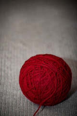 red ball of yarn on gray crocheted blanket with copy space 