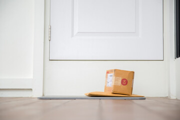 Cardboard parcel box near door on floor. Online shopping, boxes delivered to your front door. Easy...