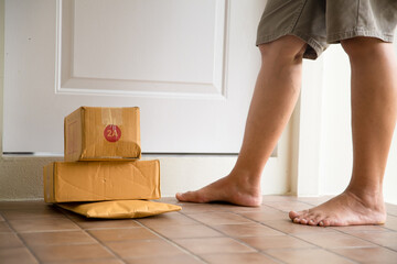 Woman collects parcel at door. box near door on floor. Online shopping, boxes delivered to your...