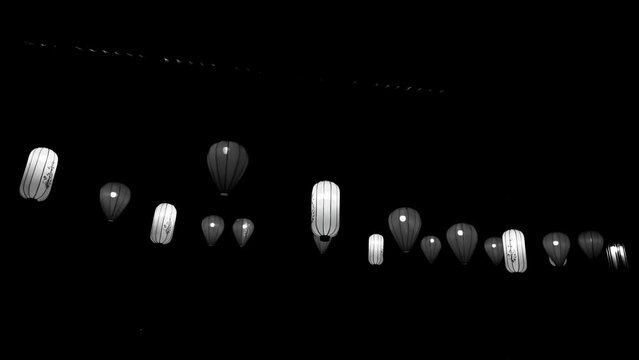 Several hanging paper lanterns, beautifully lit at night. The lantern swayed in the wind.