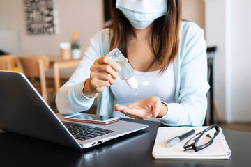 Asian girl in face mask apply hand sanitizer gel onto her hands during the coronavirus crisis. Wear a mask in public places and wash your hands to prevent the spread of the COVID-19 disease concept