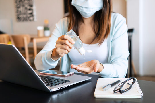 Asian girl in face mask apply hand sanitizer gel onto her hands  during the coronavirus crisis. Wear a mask in public places and wash your hands to prevent the spread of the COVID-19 disease concept