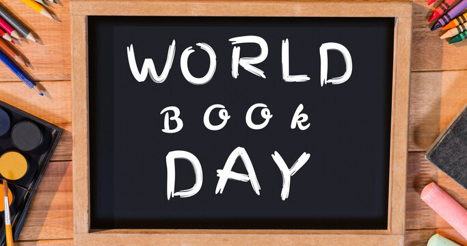 Image of world book day text over blackboard and school items on wooden background
