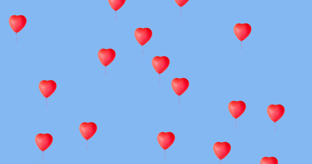 Digital image of multiple red heart shaped balloons floating against blue background