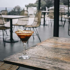 Coffee mocktail with sunkist garnish on a wooden table in an open air bar