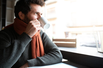Pensive man looking out the window, drinking morning coffee in coffee shop. Copy space.