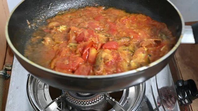 Cooking pabda fish in tomato, onion, oil on fry-pen. Slow motion video