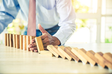 Close-up hand prevent wooden block not falling domino concepts of financial risk management and strategic planning and business challenge plan.