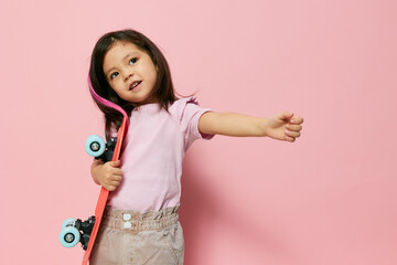 a cute little preschool girl is standing on pink in a pink T-shirt, twirling her skate in her...