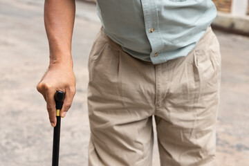 hand closeup of old senior man with either leg, knee, waist, hip pain using walking cane or walking aid device