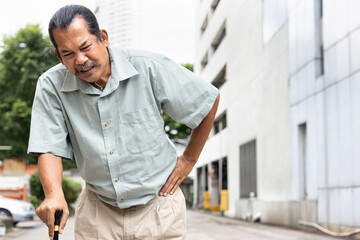 old senior man with either leg, knee, waist, hip pain using walking cane or walking aid device, concept of health care of aging society, thin bone, osteoporosis or osteoarthritis symptom