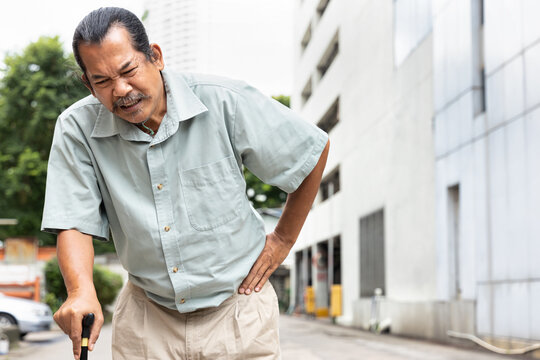 Old Senior Man With Either Leg, Knee, Waist, Hip Pain Using Walking Cane Or Walking Aid Device, Concept Of Health Care Of Aging Society, Thin Bone, Osteoporosis Or Osteoarthritis Symptom