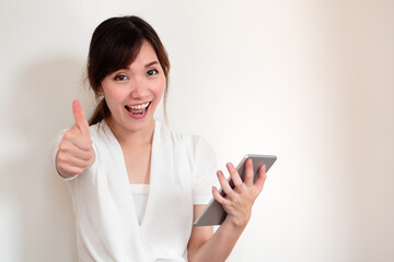 Fototapeta premium happy young casual asian woman using computer tablet showing thumb up gesture