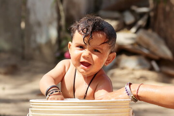 happy Baby having a bath in the water Bucket, Rajasthan India