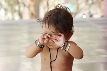 Indian hindu Baby boy kid covering close his eyes with hands with with funny expression, Rajasthan India