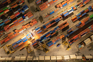 Aerial view of container cargo ship in the export and import business and logistics international goods in urban city. Shipping to the harbour by crane in Bangkok harbour, Thailand at night.