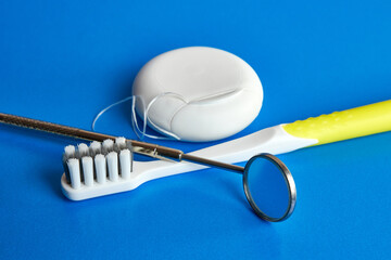 Dental mirror, dental floss and toothbrush on a blue background. Dental care.