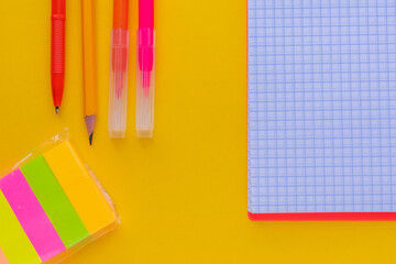 Notepad, stickers, pen, pencil and markers on yellow table. View from above. Memo tools