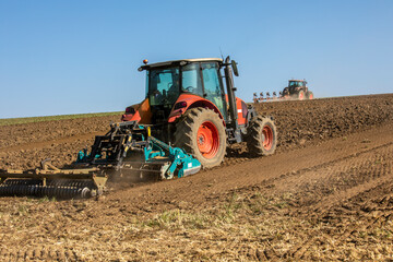 Agriculteur au volant de son tracteurs travaillant la terre au printemps.
