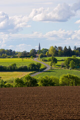Petit village fran&ccedil;ais en campagne avec son cloch&eacute; au milieu des champs en France.