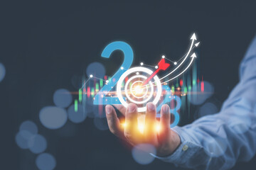 Analysts holding the year 2023 with a stock high growth graph on hand. Planning strategy investment to stock, and analyzing marketing for high profit. Business, Investment, and financial concepts.